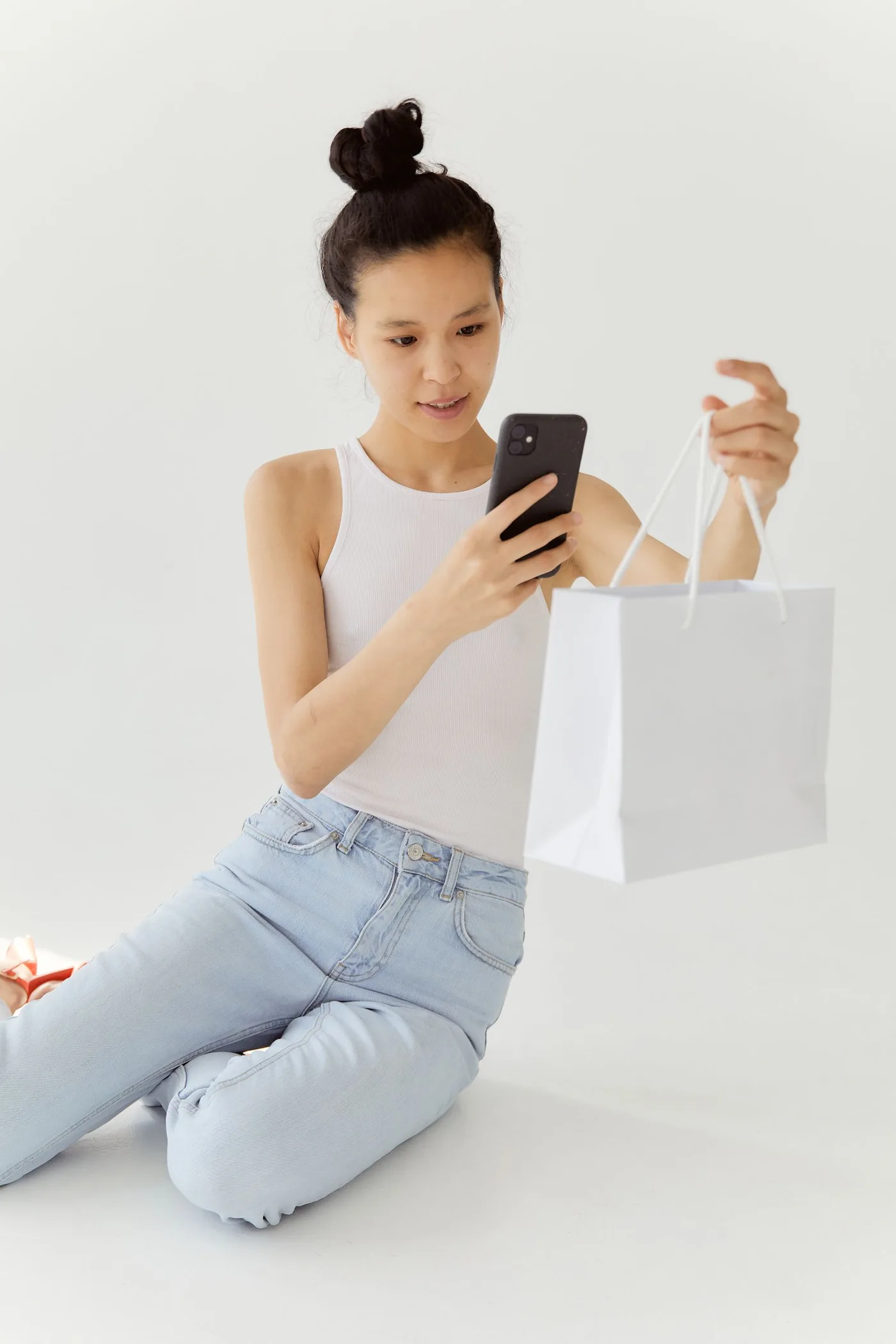 Una joven con su celular y una bolsa de compras